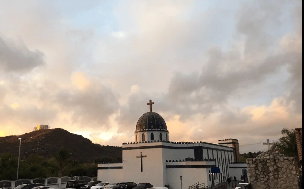 The dome and cross of St. Peter Chaldean Catholic Cathedral against the evening sky