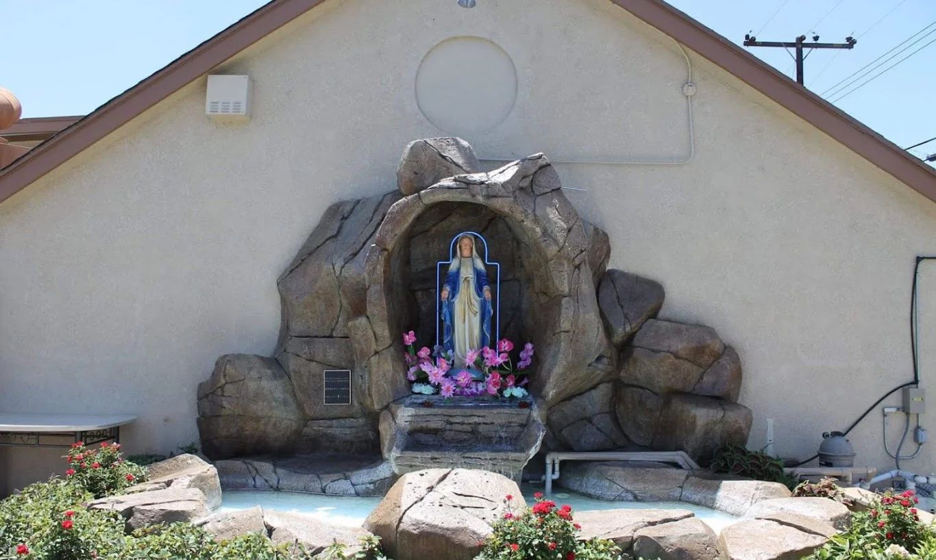 A statue of the Virgin Mary in a rock grotto with flowers at St. George