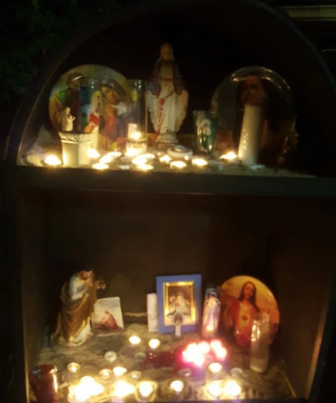 Candles and flowers at a shrine at night